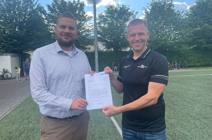 A photo of two people holding a donation letter from a bank, standing side by side.