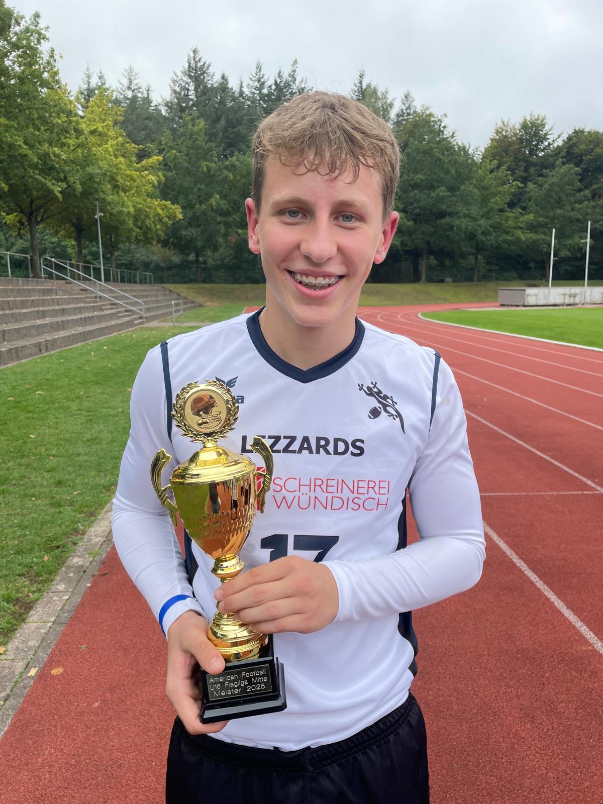 Eine Nahaufnahme von MVP Ilias Secolo, der die Trophäe in der Hand hält.