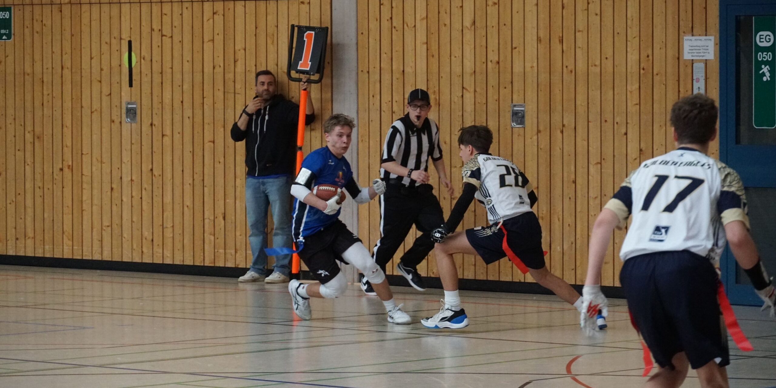 Ein Spieler rennt mit dem Ball, während die anderen beiden versuchen, ihn zu tackeln.
