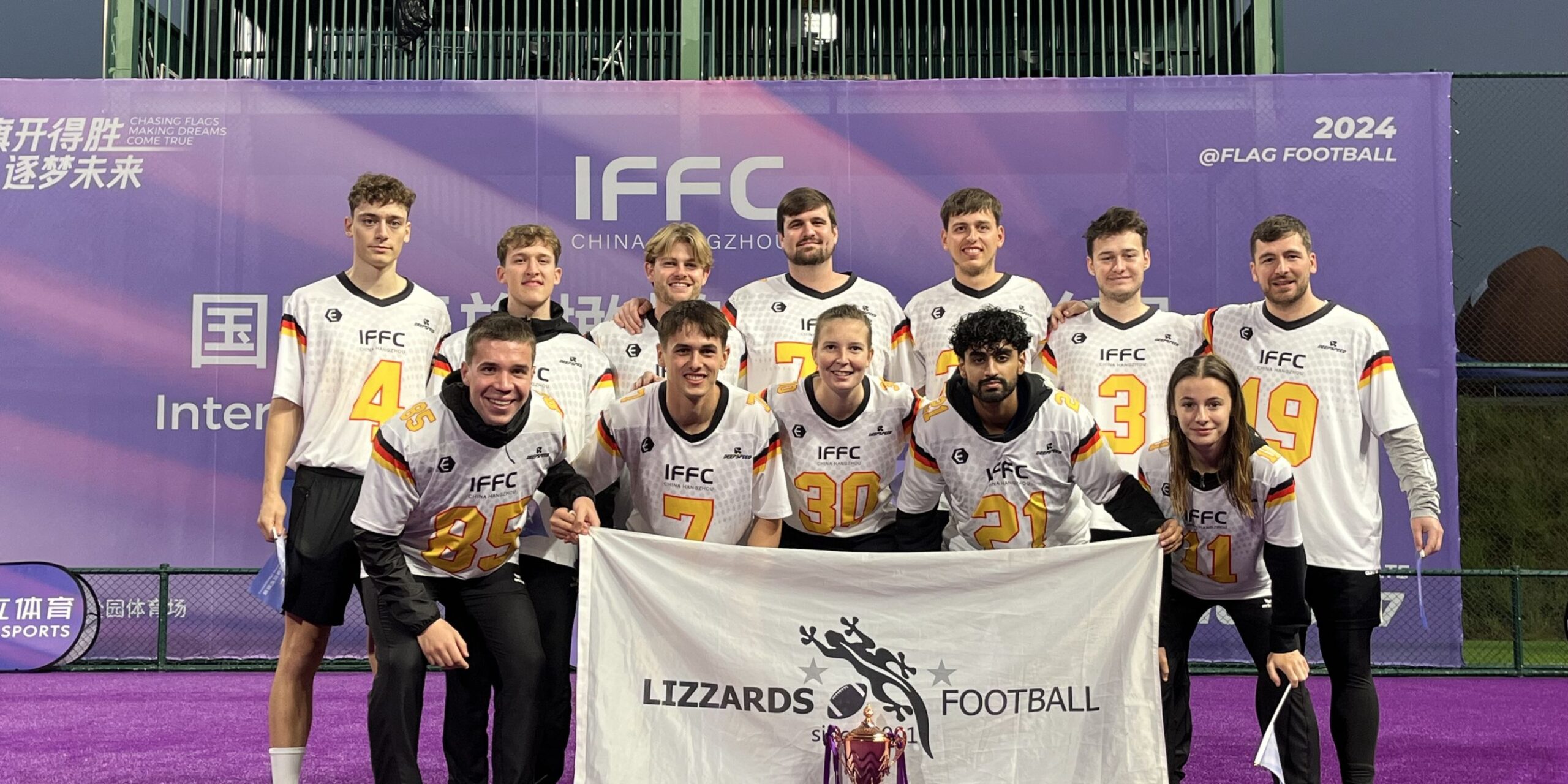 Gruppenfoto des Teams aus Kelkheim mit ihrem Pokal bei der Internationalen Flag-Football-Meisterschaft, auf dem sie das Banner von Lizzards Football halten – 2