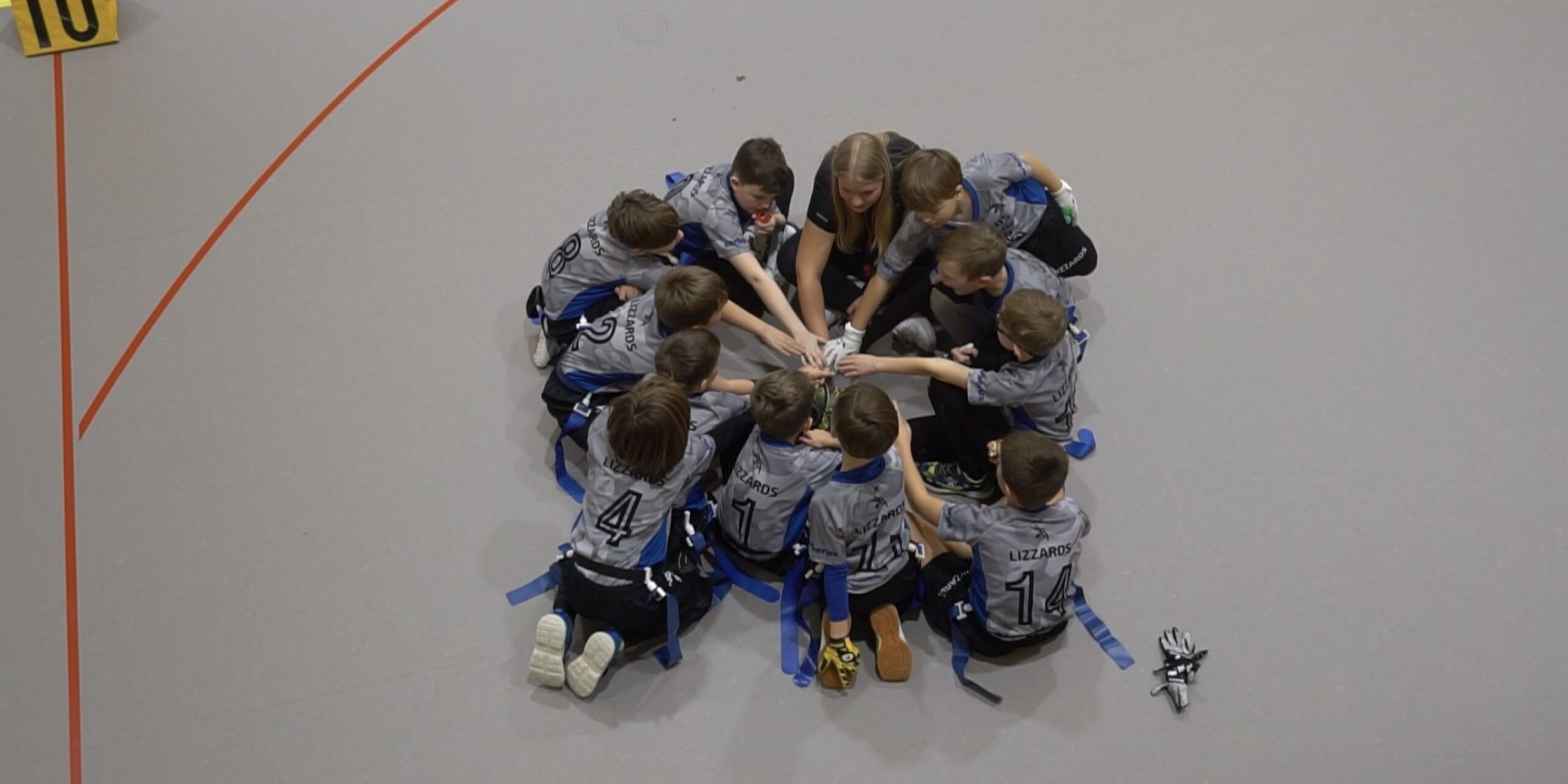 Kelkheim-Spieler, die eine Handstapelgeste machen, während sie in einem engen Kreis auf dem Boden sitzen