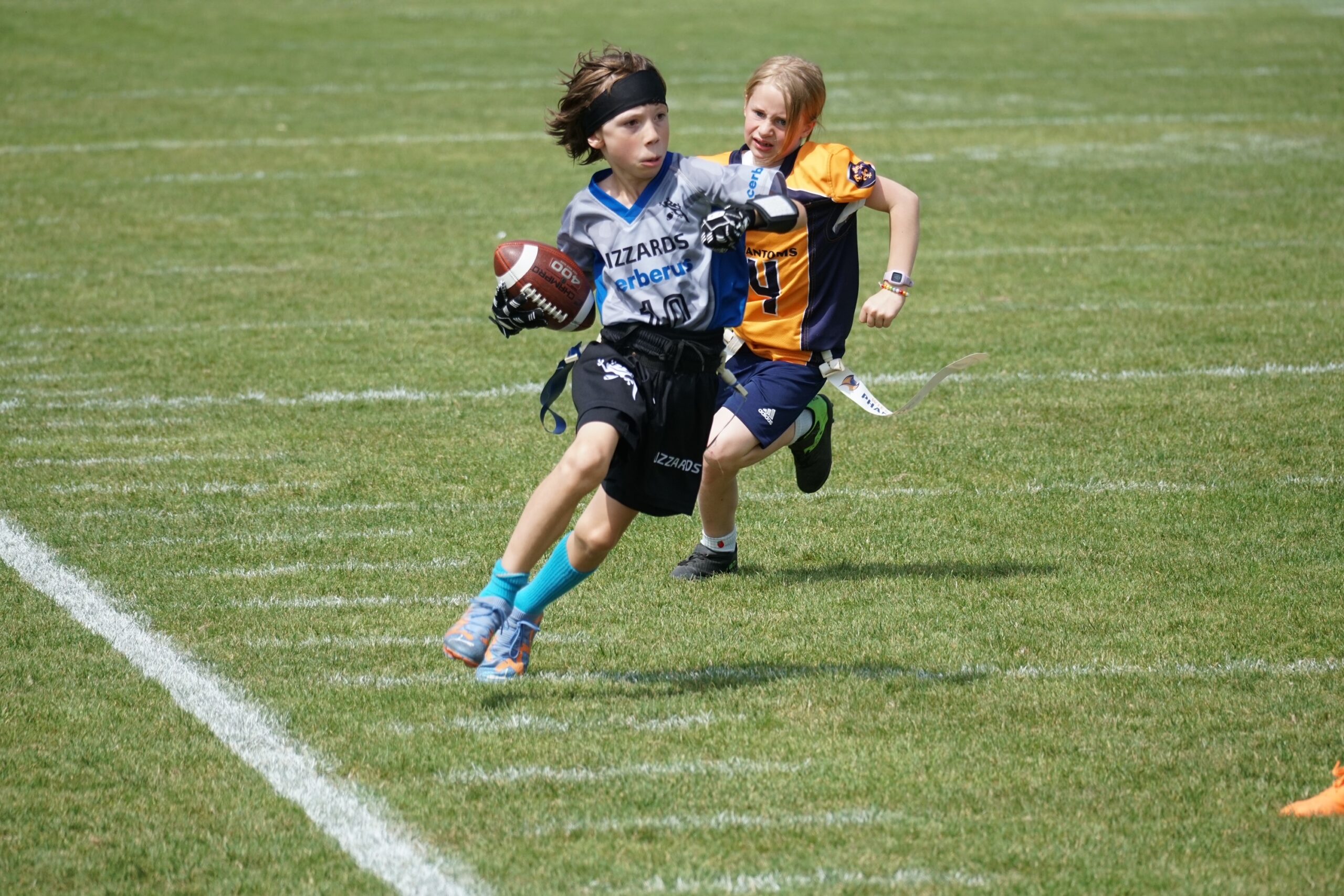 Ein Spieler der U10-Mannschaft von Kelkheim läuft mit dem Ball, während er von einem Spieler der gegnerischen Mannschaft auf dem Spielfeld verfolgt wird.